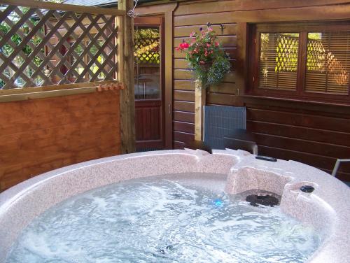 eine Whirlpool-Badewanne im Hinterhof eines Hauses in der Unterkunft Cypress Log Cabins Accommodation in Godshill