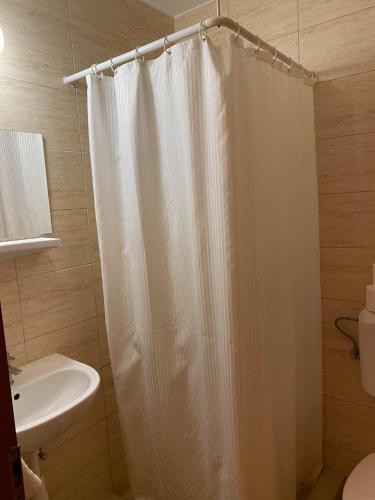a bathroom with a white shower curtain and a sink at Tapolca Fogadó in Miskolctapolca