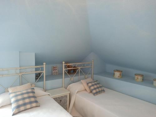 two beds in a room with blue walls at Duplex céntrico en Noja con acceso a spa relax. in Noja