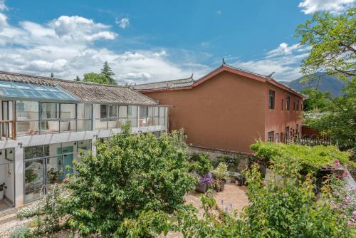 a house with a garden in front of it at Baisha Flamingo Hotel in Lijiang