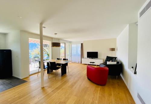 sala de estar con silla roja y mesa en Panorama Boutique Apartment with Air Condition, SPA entry in Solbadhotel, en Sigriswil