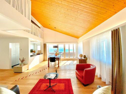 un soggiorno con tavolo e sedia rossa di Panorama Boutique Apartment with Air Condition, SPA entry in Solbadhotel a Sigriswil