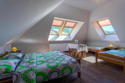 a attic bedroom with two beds and a table at Hortensja Pokoje Gościnne in Krościenko
