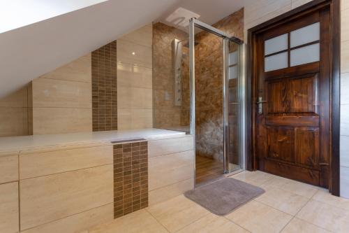 a bathroom with a walk in shower next to a wooden door at Hortensja Pokoje Gościnne in Krościenko