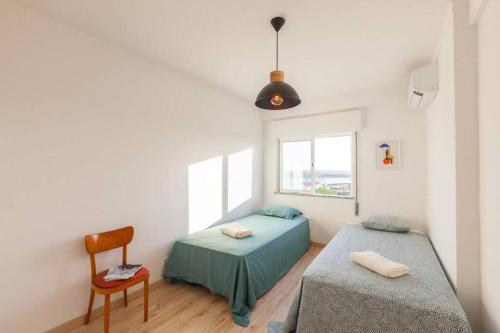 a bedroom with two twin beds and a chair at Sunset entre a Ria e o Teatro in Faro