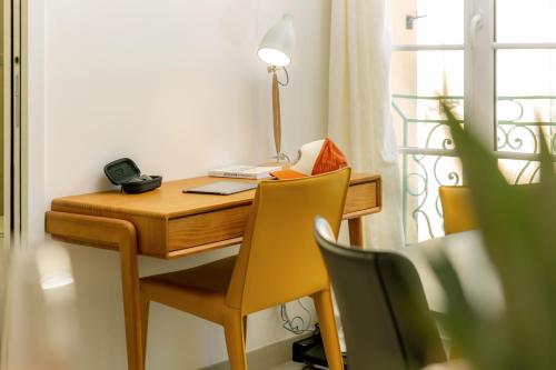 a desk with a lamp and two chairs in a room at Provence Au Coeur Appart Hotels in Forcalquier