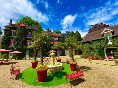 une cour avec une fontaine en face d'un bâtiment dans l'établissement Manoir des Cavaliers - BnB, à Chantilly