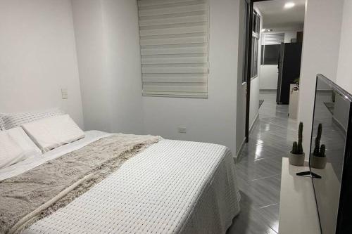 a white bedroom with a bed and a mirror at Hermoso Apartaestudio en Sabaneta. in Sabaneta