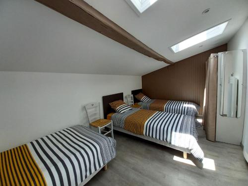 a room with two beds and a chair in it at Gîte "Chez Marcel et Cie" - 8 mn du Puy du Fou in Les Herbiers