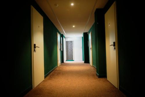 an empty hallway with green walls and a long corridor at Hotel Union in Offenburg