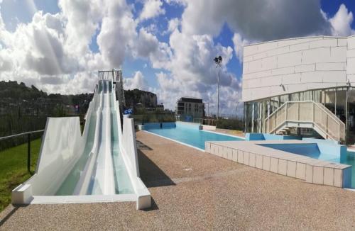 een zwembad met een glijbaan voor een gebouw bij Au bord de Mers in Mers-les-Bains