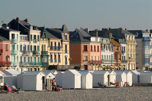 een groep strandhutten op het strand met gebouwen bij Au bord de Mers in Mers-les-Bains