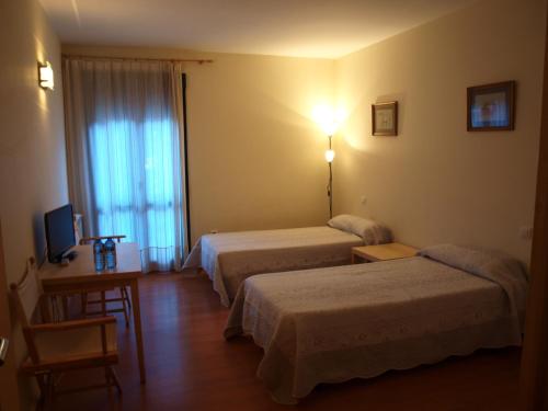 a hotel room with two beds and a television at Apartamentos Turísticos La Peña in Baños de Montemayor