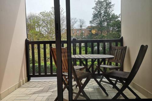 une table et des chaises sur un balcon avec une fenêtre dans l'établissement Appartement 2 personnes à 300m de la mer, à Cabourg