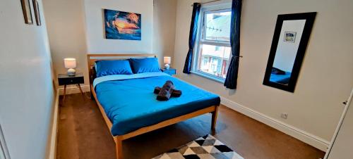 a bedroom with a bed with blue sheets and a mirror at Rhubarb Terrace on the Coast - Sleeps 1-6 in Colwyn Bay