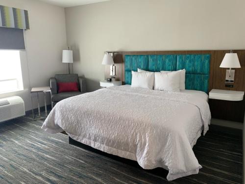 莫纳汉斯Hampton Inn Monahans, Tx的配有一张大床和一把椅子的酒店房间