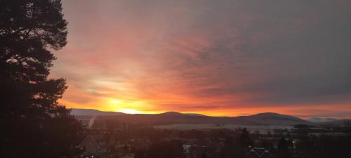 um pôr-do-sol sobre uma cidade com montanhas ao fundo em Ardvonie House em Kingussie