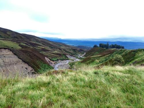a view of a river on a hill with grass at Ardvonie House in Kingussie