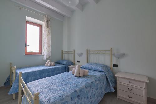 a bedroom with two beds with blue sheets and a window at La rosa dei venti, apartment 3 in Porto Empedocle