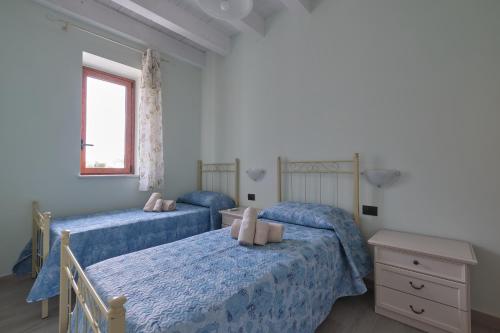 sypialnia z 2 łóżkami z niebieską pościelą i oknem w obiekcie La rosa dei venti, apartment 3 w mieście Porto Empedocle
