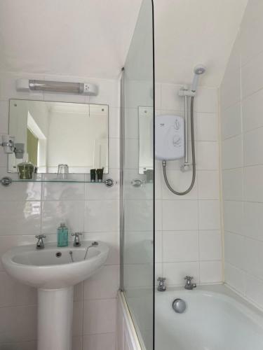 a white bathroom with a sink and a shower at West Lodge Hotel in Aylesbury
