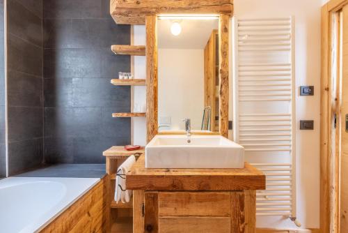a bathroom with a sink and a tub and a mirror at Casa Olimpia in Cortina dʼAmpezzo