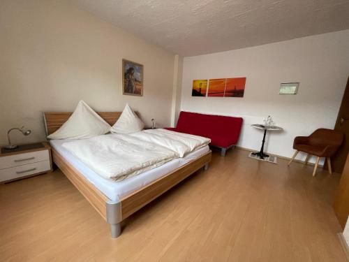 ein Schlafzimmer mit einem weißen Bett und einem roten Stuhl in der Unterkunft Hotel und Gästehaus Gute Quelle in Cochem