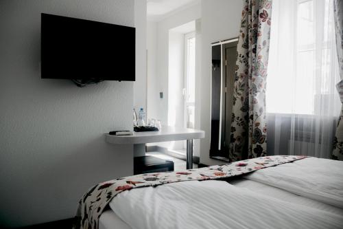 ein Schlafzimmer mit einem Bett und einem TV an der Wand in der Unterkunft Customs House Hotel & SPA in Rostow am Don