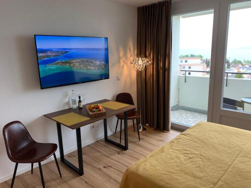 a hotel room with a table and a television on the wall at Apartment TraumSeeblick Immenstaad in Immenstaad am Bodensee