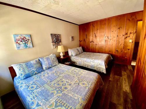 a bedroom with two beds and wooden walls at Turn of River Lodge in Killington