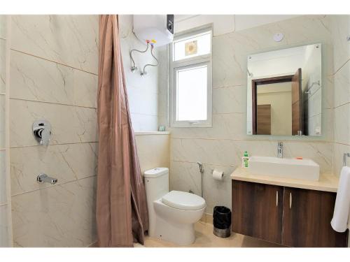 uma casa de banho com um WC, um lavatório e um espelho. em BluO Studio4 Golf Course Road - Gym, Balcony, Lift em Gurgaon