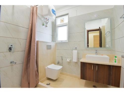 a bathroom with a sink and a toilet and a mirror at BluO Studio5 Golf Course Road - Gym, Terrace Garden in Gurgaon