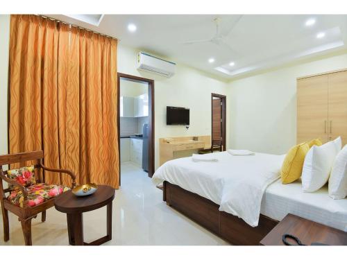 a bedroom with a bed and a chair and a television at BluO Studio5 Golf Course Road - Gym, Terrace Garden in Gurgaon