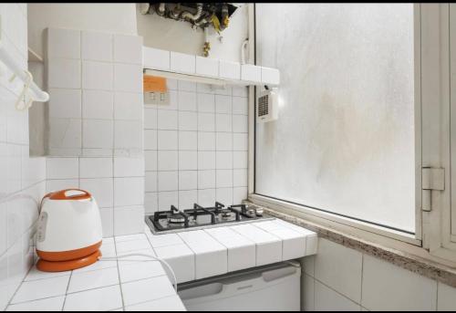 a white tiled bathroom with a sink and a window at MELLINI HOUSE in Rome