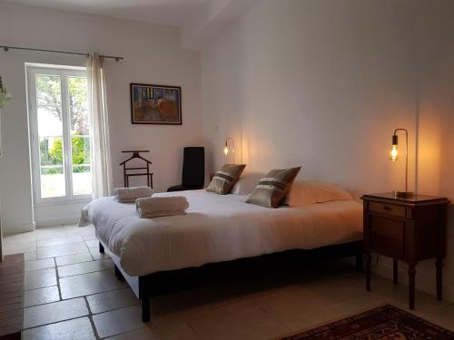 a bedroom with a large bed and a window at Domaine de Pelouaille - chambre d'hôtes in Saint-Jean-dʼAngély