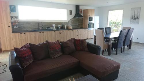 un salon avec un canapé marron et une cuisine dans l'établissement LOCANOMA, à Corbara