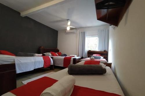 a room with three beds with red and white at Pousada Aquarela Pirenopolis in Pirenópolis