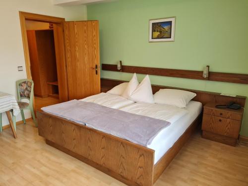 a bedroom with a large wooden bed with white pillows at Edelsteinhotel Guniwirt in Krakaudorf