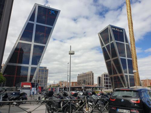 two tall buildings with bikes parked in a parking lot at Bonito Apto Cinco Torres Plaza Castilla in Madrid