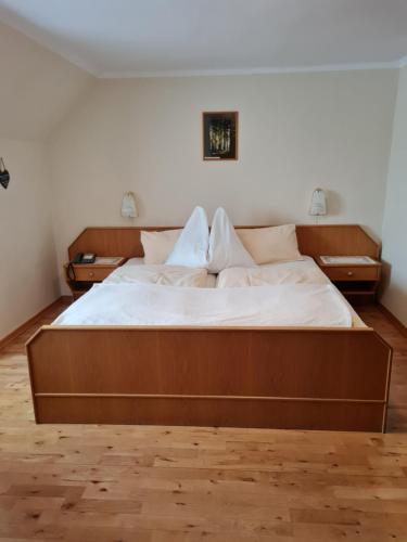 a large wooden bed in a room with two night stands at Edelsteinhotel Guniwirt in Krakaudorf
