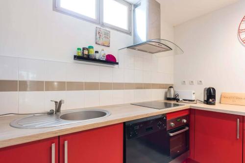 - une cuisine avec des placards rouges et un évier dans l'établissement studio next to bordeaux city center with a terrace, à Bègles