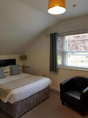 a bedroom with a bed and a chair and a window at Tirah Guest House in Aldeburgh