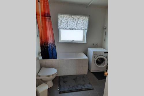 ein Badezimmer mit einer Badewanne, einem WC und einer Waschmaschine in der Unterkunft The red house near the sea in Njarðvík