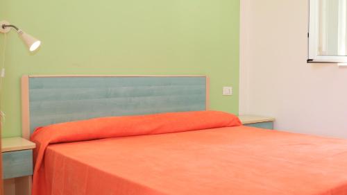 a bed with an orange blanket on top of it at Villaggio Elisena in Vieste