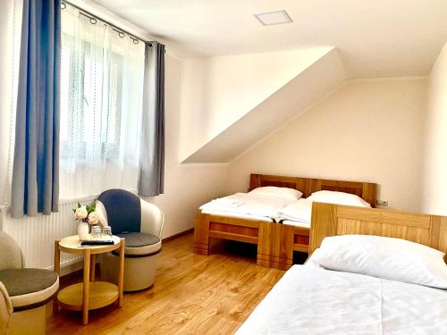 1 dormitorio con 2 camas, silla y ventana en Penzion pod Tureckom, en Trenčianske Bohuslavice