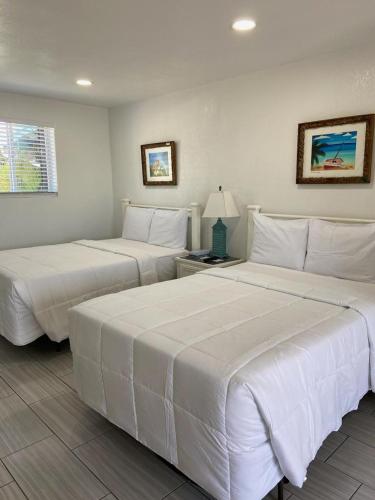 two beds in a hotel room with white sheets at Edgewater Lodge in Layton