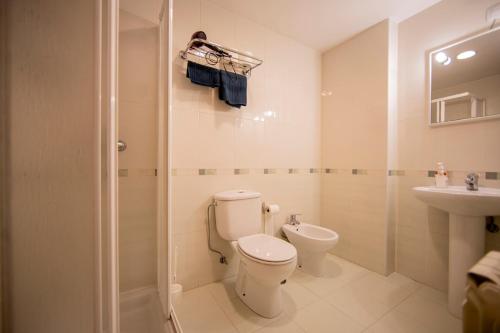 a bathroom with a toilet and a sink and a shower at Noja Rooms in O Pedrouzo