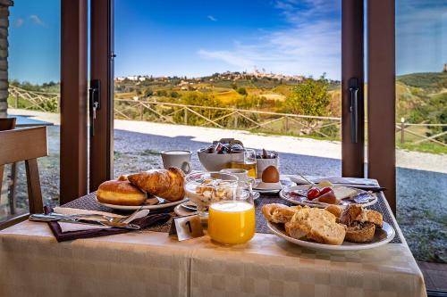 une table avec un petit-déjeuner composé de pain et de jus d'orange dans l'établissement Agriturismo Poggiacolle, à San Gimignano