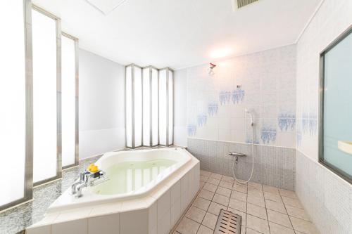 a white bathroom with a tub and a shower at Hotel Chapel Sweet (Adult Only) in Kobe