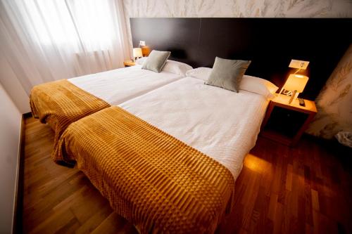 オ・ペドロウソにあるNoja rooms 1の黄色い毛布が掛けられた大きなベッドのある寝室